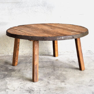 Table basse ronde avec trois pieds en bois massif et un bord en métal antique provenant d'une roue en métal antique.